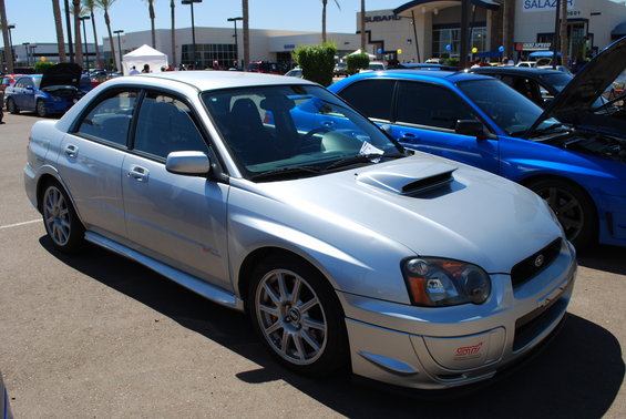 Silver Subaru Impreza WRX STI sedan, front 3/4 view, with hood scoop and STI badge on front bumper