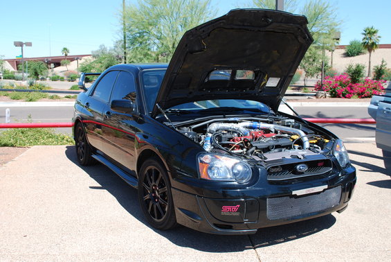 Black Subaru Impreza WRX STI with hood open, showing engine. Has 'STI' badge on front bumper