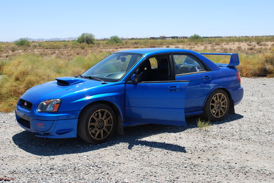 Blue 2005 Subaru Impreza WRX STI with doors open, parked on gravel