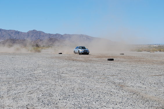 Silver 2005 Subaru Impreza driving on a dirt track, kicking up dust