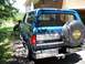 1995 Ford Bronco - The rear of a blue 1995 Ford Bronco is visible, a spare tire cover with the Harley-Davidson Cycles logo.