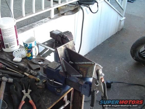 Metal bracket clamped in vise, ready for welding