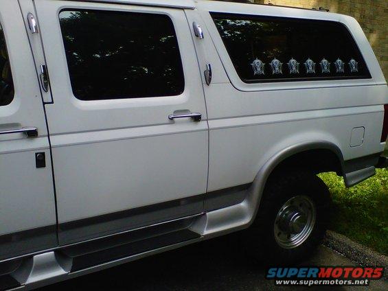 Side view of a white conversion van with tinted windows and chrome trim