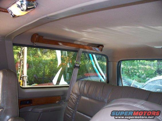Interior view of a vehicle's back seats and windows, showing trees outside