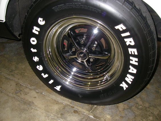 Close-up of a Firestone Firehawk tire with white lettering on a chrome rim