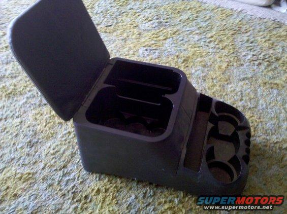 Black plastic center console organizer with open lid, multiple compartments, and cup holders