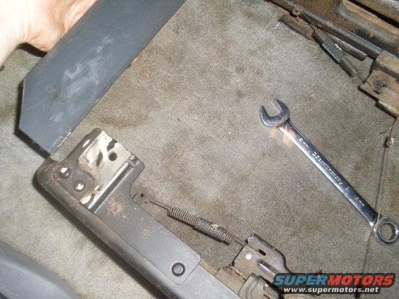 Close-up of car seat adjustment mechanism with a wrench on the carpet