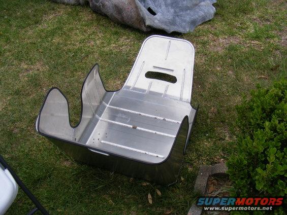 Aluminum racing seat with side bolsters and headrest cutouts, sitting on grass