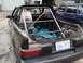 1989 Ford Escort - This car has been modified with a roll cage and racing seat, with a blue tarp covering items in the rear.
