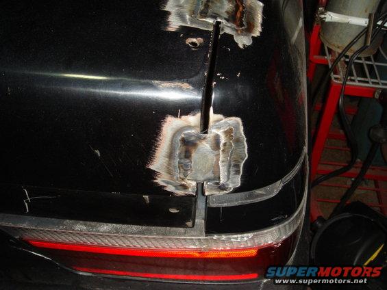 Black car trunk with visible welding repairs along the center seam and around the taillight area