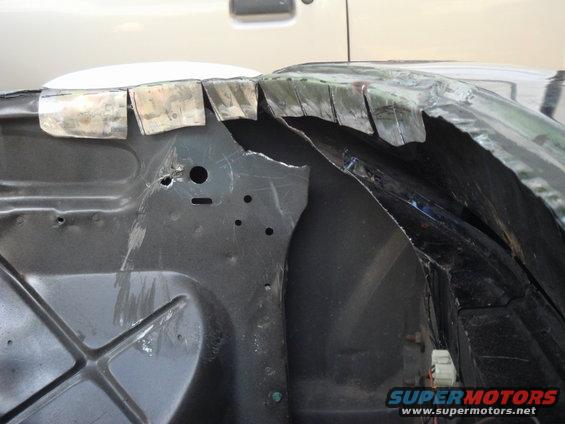 Car fender well with cut metal tabs and exposed inner structure