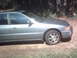 1994 Honda Accord - The side profile of a silver sedan is visible, with a flat front passenger tire and trees behind it.