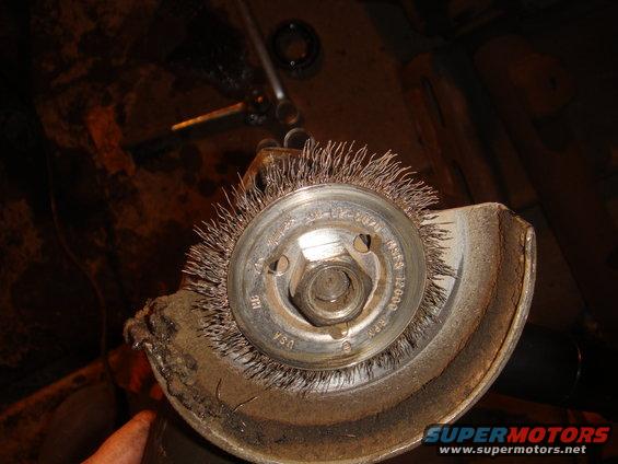 Wire wheel brush attached to an angle grinder, showing rust and wear