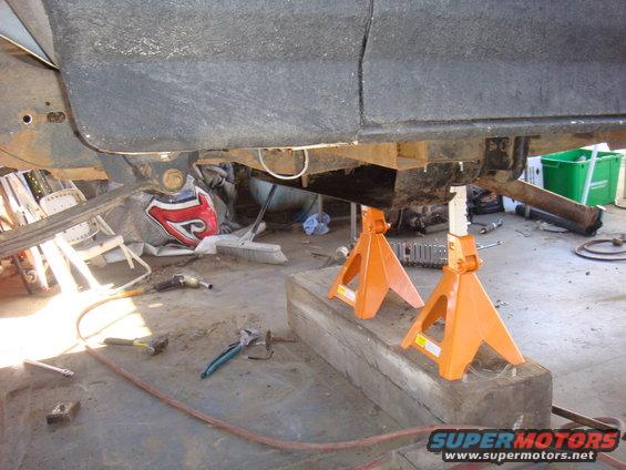 Vehicle underbody on jack stands with tools on the floor