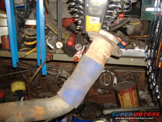 exhaust pipe with blue wrap, surrounded by tools and parts in a workshop