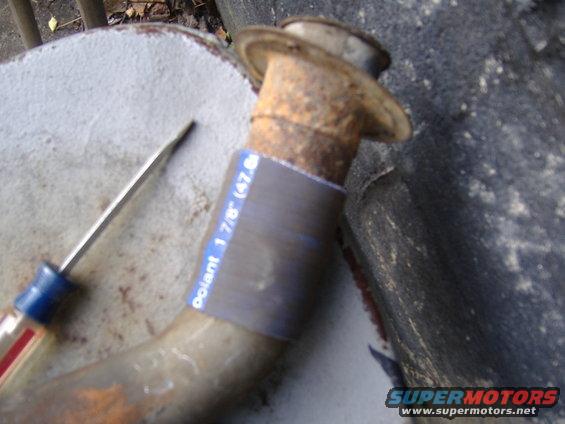Rusted pipe with blue and white tape showing measurements, next to a screwdriver