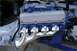 1972 Ford Ranchero - Engine with blue block, Cobra valve covers, and chrome headers, suspended by chains.