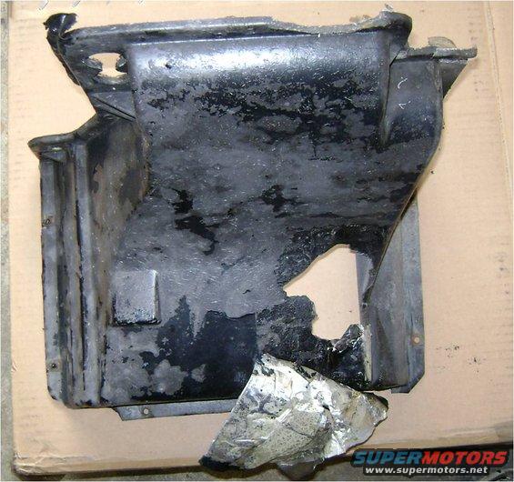 damaged black plastic undercarriage part with a hole torn in it and some foil attached