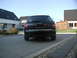 2003 Audi A6 - A black Audi A6 station wagon is parked in a driveway, with houses and a green car in the background.