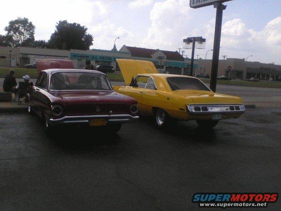 Maroon 1960s Ford Falcon and yellow 1970s Dodge Dart parked side-by-side, both with hoods open