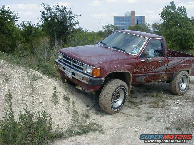 Maroon Toyota pickup truck with off-road tires on a dirt hill