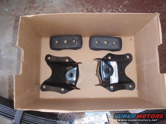Cardboard box with four black suspension parts and leaf springs