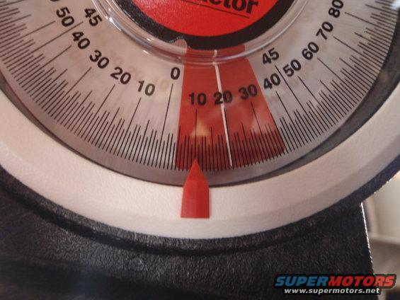 Close-up of a red and white angle gauge with black markings and a red pointer