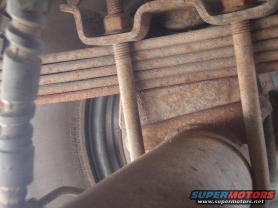 Close-up of rusty leaf springs and U-bolts over a tire