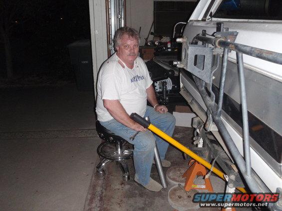 Man working on vehicle suspension with yellow tool