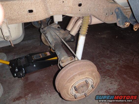 Rear axle assembly with drum brake and shock absorber, supported by a floor jack