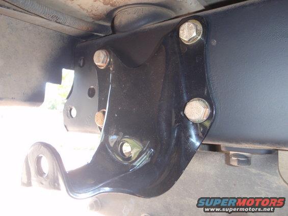 Close-up of a black metal bracket bolted to a vehicle's frame
