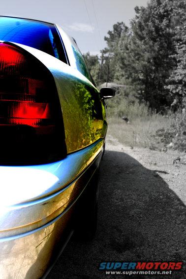 2002 Ford Crown Victoria rear quarter panel and taillight, parked on a dirt road