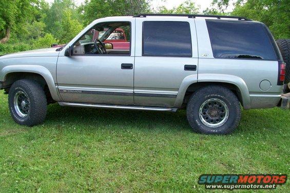 Silver 2000 Chevrolet Tahoe parked on grass, another red vehicle visible through the driver's side window