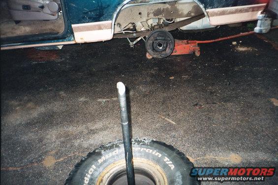 Teal and tan SUV side view, rear axle removed, tire on ground