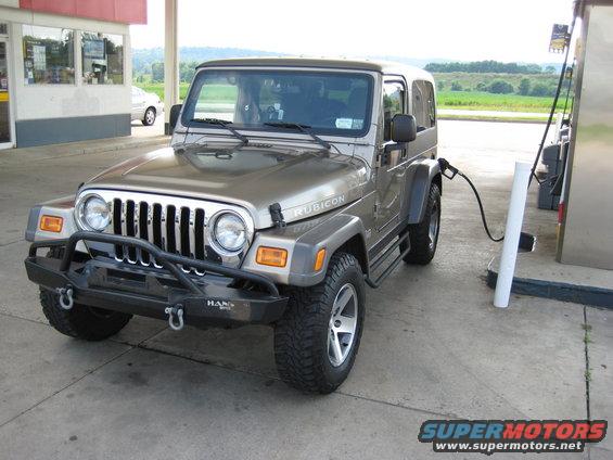 Tan Jeep Wrangler Rubicon fueling up at a gas station
