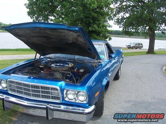 Blue 1973 Ford Ranchero with hood open, parked by a lake
