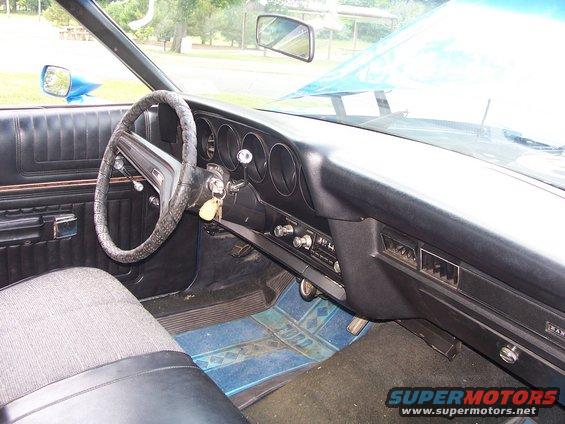 1973 Ford Ranchero interior showing dashboard, steering wheel, and seats. Blue floor mats have 'FORD' logo