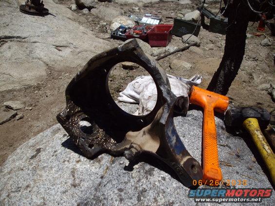 Disassembled vehicle part on rock with tools