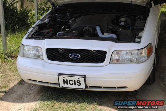 White Ford Crown Victoria with hood open showing engine. NCIS license plate visible