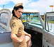 1963 Ford F-100 - A woman in a vintage military-style uniform poses inside the cab of a 1963 Ford F-100 pickup truck.