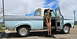 1963 Ford F-100 - A woman poses by a light blue and grey pickup truck with the driver's door ajar.