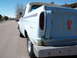 1963 Ford F-100 - A light blue pickup truck is seen from the rear quarter, with visible rust and a sticker on its tailgate.