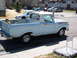 1963 Ford F-100 - A child sits in the bed of a light blue pickup truck parked on a residential street.