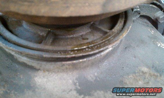 Close-up of a greasy metal component, possibly part of a drivetrain, with a SuperMotors logo visible