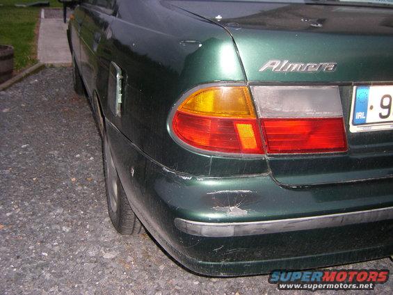 Green 1998 Nissan Almera, rear view, showing bumper damage and Irish license plate
