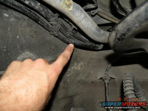 Hand pointing at brake lines and hoses under a vehicle. Date stamp reads 06.30.2010