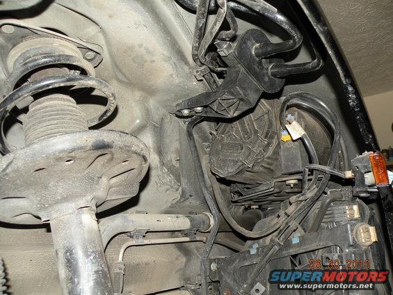 Close-up of car's front suspension strut and engine bay wiring harness