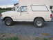 1989 Ford Bronco - A white Ford Bronco is parked on a gravel surface next to a building. The vehicle is viewed from the side.