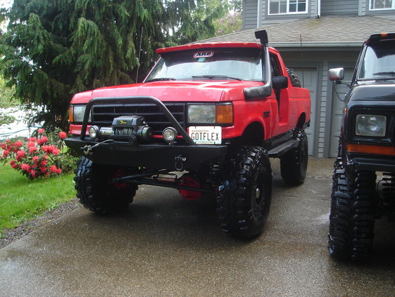 1989 Ford Bronco modified for off-roading, parked next to another vehicle