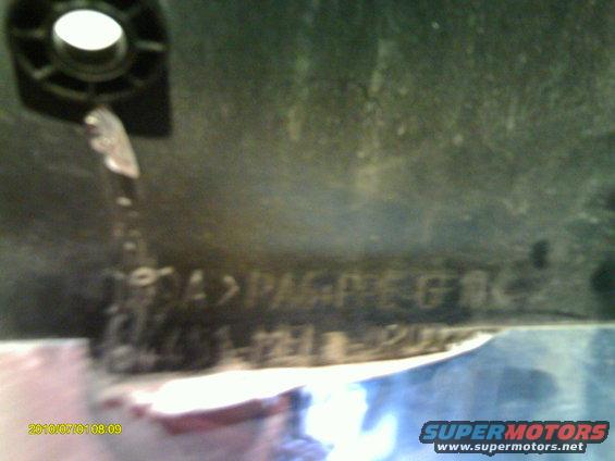 Close-up of a dark plastic part with embossed text including 'PAG-PEG-61K' and '121-121-202'